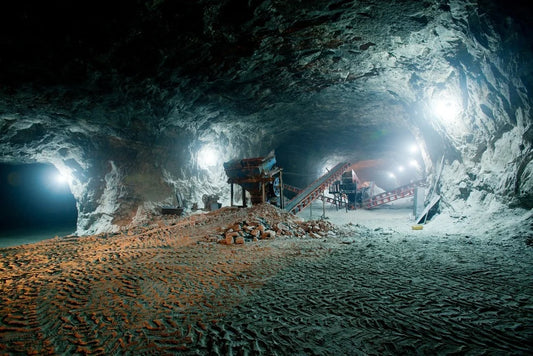 Under­ground mine tunnel with thick armored cabling running along rock walls — Explosion Proof Cables Australia